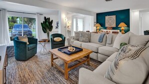 Una sala moderna con sofá, sillón, mesa de centro y un ventanal con vista a un coche.