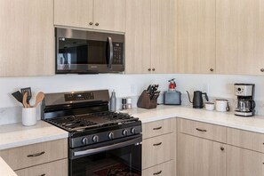 Eine moderne Küche mit Gasherd, Mikrowelle und diversen Geräten.