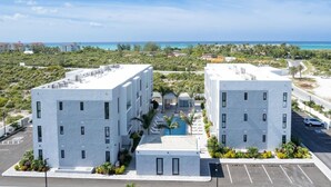 Un hôtel moderne composé de deux bâtiments blancs, doté d’une piscine et offrant une vue sur l’océan.