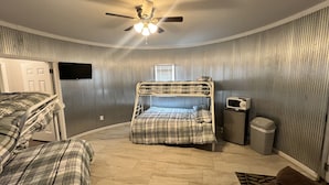 Ein Zimmer mit Etagenbett, Deckenventilator, Mikrowelle und Mülleimer.