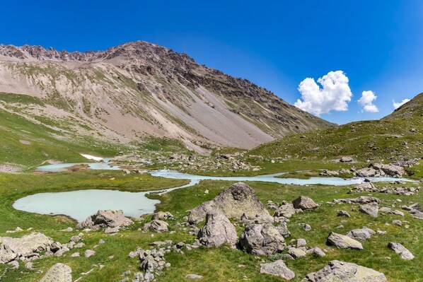 Paisaje montañoso con terreno rocoso y un lago pequeño.
