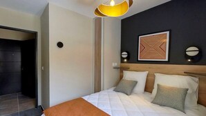 Un dormitorio moderno con una cama grande, cabecera de madera y una original pieza de arte mural geométrico.
