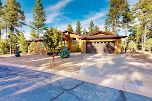 A two-story house with a garage, surrounded by tall pine trees. - Pristine Torreon Cabin, Sleeps 6 (Show Low)