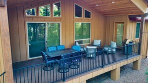 A wooden deck with a table and chairs, a grill, and a covered area with windows. - Pristine Torreon Cabin, Sleeps 6 (Show Low)