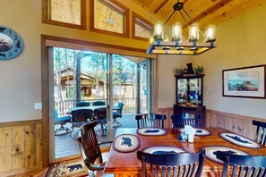 Un coin repas en bois avec une grande table, des chaises et un lustre.