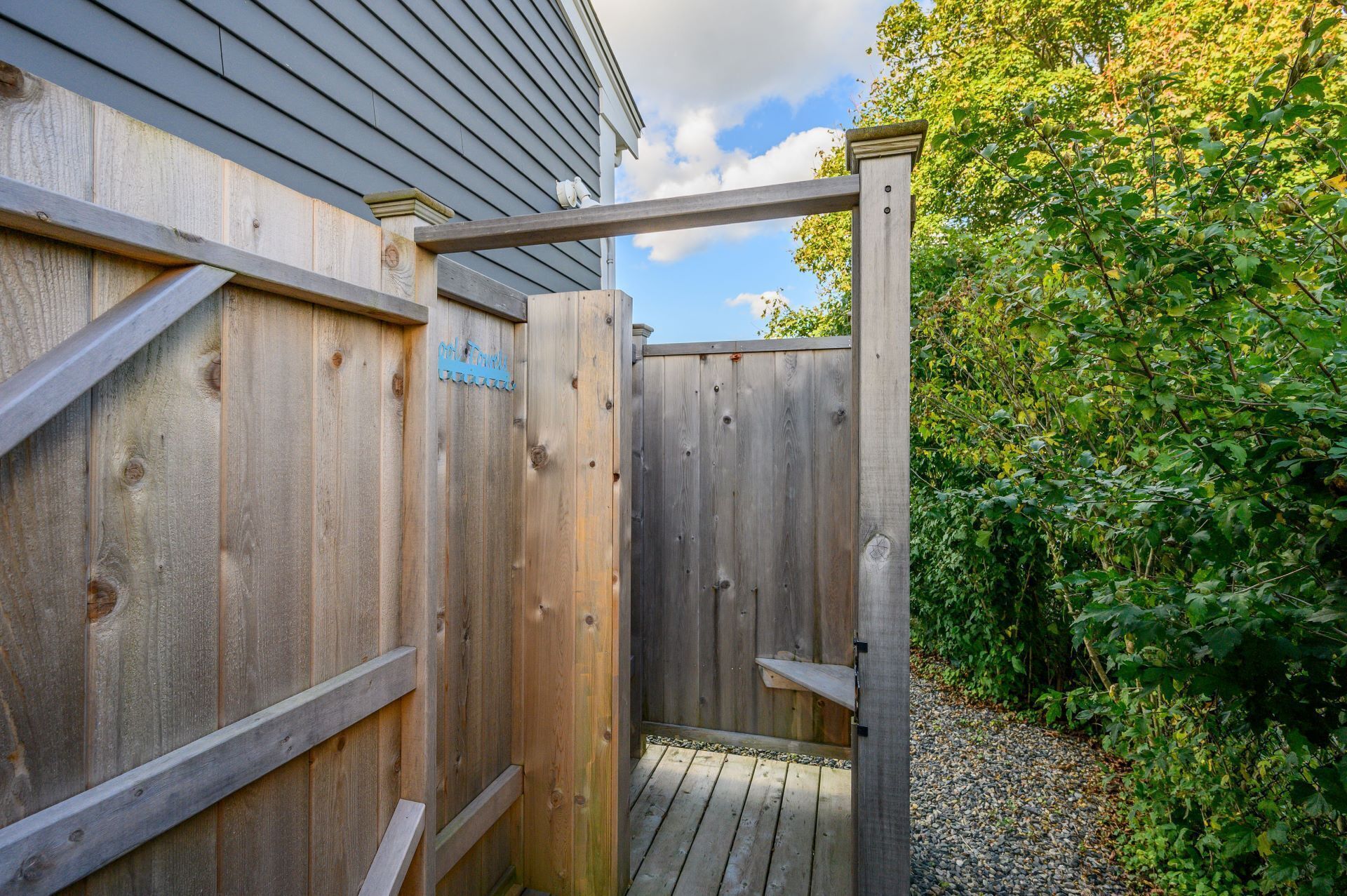 Une porte en bois mène à un espace extérieur abrité, accessible par un chemin de gravier.