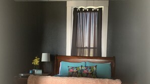 Une chambre à coucher avec un lit en bois, une couverture rose et moelleuse, et une table de chevet avec une lampe et des fleurs.
