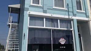 Un bâtiment à deux étages avec une grande vitrine donnant sur la rue, où est affiché un panneau indiquant qu’il s’agit d’une boulangerie.