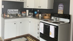 Une cuisine avec des meubles blancs, une cuisinière et un évier.