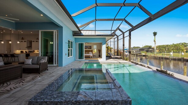 Et moderne hus med swimmingpool, en glasindkapslet terrasse og udsigt til vandet.