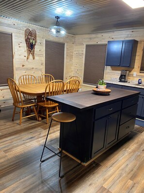 A modern kitchen with a wooden dining table, chairs, and a central island with stools.