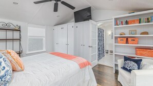 A bedroom with a bed, wardrobe, ceiling fan, TV, and a bookshelf. - Darling Beach House with Private Pool! (Tybee Island)