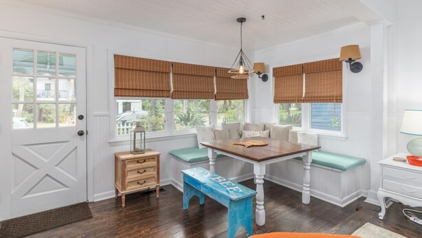 A dining area with a wooden table, benches, and a bench with 'MIXBEEF' written on it. There is a wooden chest of drawers and a small table with a lamp. - Darling Beach House with Private Pool! (Tybee Island)