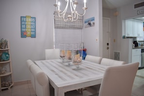 A dining area with a white table and chairs, a chandelier, and decorative items on the wall.