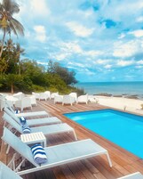 Una piscina al aire libre, sombrillas, tumbonas