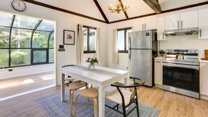 Una cucina moderna con un'ampia finestra, travi in legno, elettrodomestici in acciaio inossidabile e un'area pranzo con tavolo e sedie.