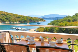 Enjoy a meal on the balcony with a serene view of the water and surrounding hills.