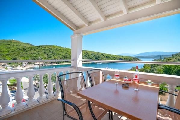 Enjoy a serene view of the water and surrounding hills from this balcony, complete with a table for al fresco dining.