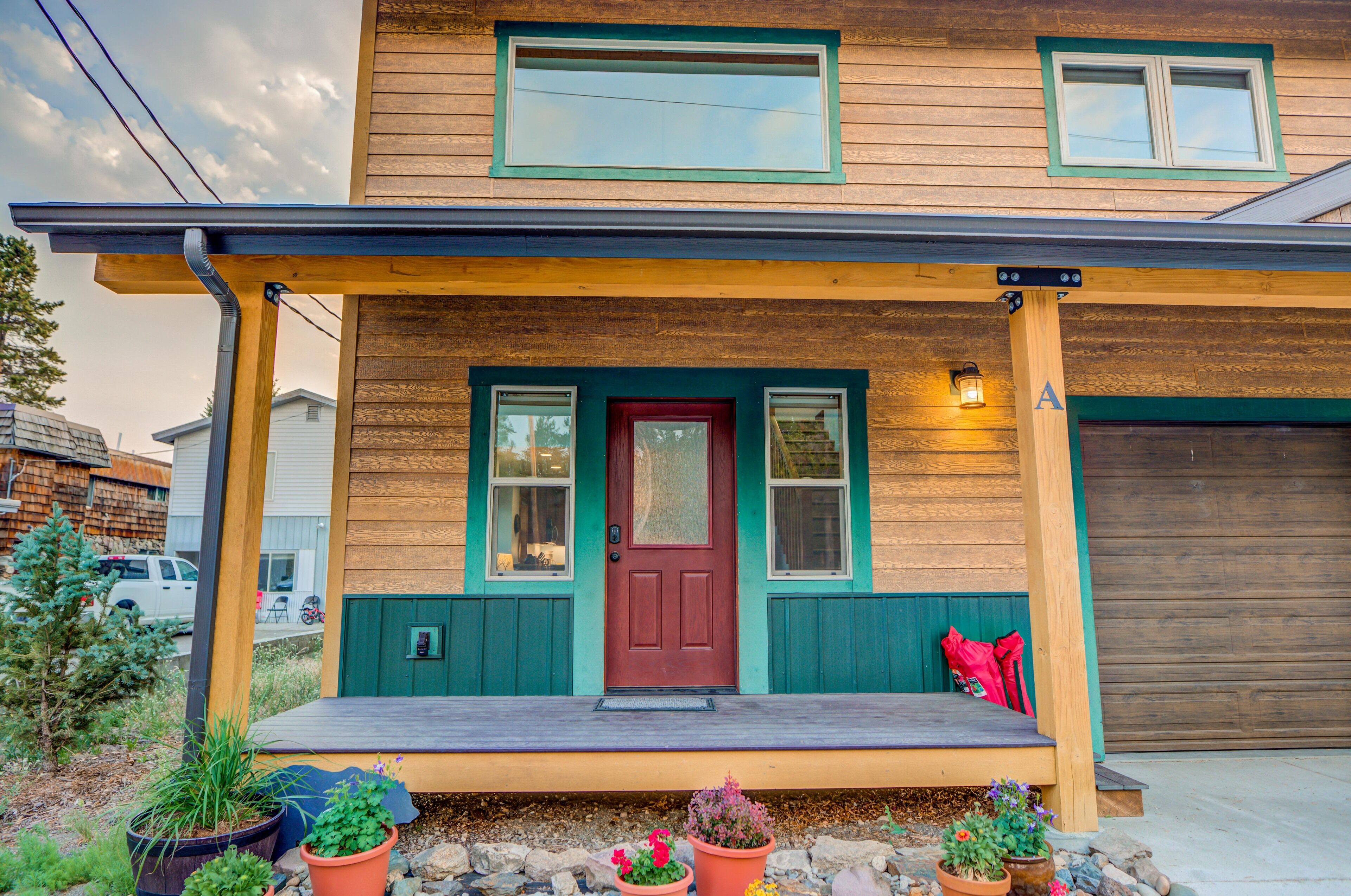 A two-story house with a red door, a front porch, and a garage.