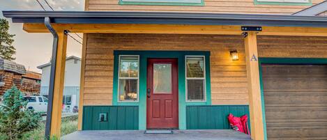 A two-story house with a red door, a front porch, and a garage.