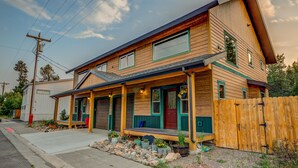 A two-story house with a porch, a garage, and a wooden fence. - Barnes on Boundary Unit A (West Yellowstone)