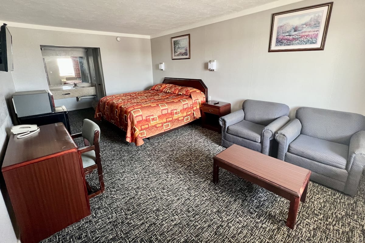 A hotel room with a bed, a desk, a chair, a couch, and a small table.