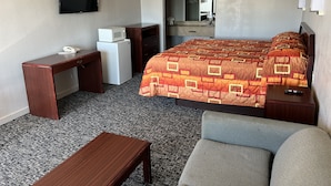 A hotel room with a bed, a desk, a chair, a TV, a microwave, and a small refrigerator. - Hotel 81 El Reno (El Reno)