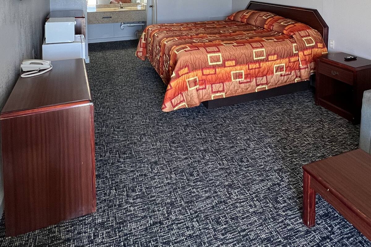 A hotel room with a large bed, a desk, a chair, a TV, and a picture on the wall.