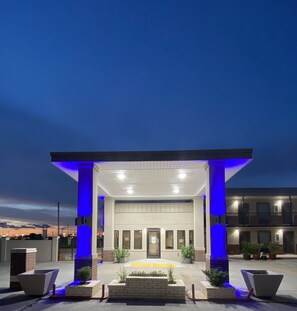 A modern building with a covered entrance, columns, and a well-lit facade.