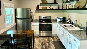 Una cocina moderna con electrodomésticos de acero inoxidable, una mesa de comedor de madera y un horno empotrado.