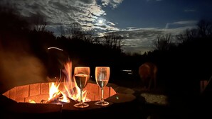 Una chimenea con dos copas de vino, chimenea de ladrillo y un cielo nocturno con nubes.