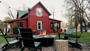 Una casa roja con una chimenea exterior y asientos al aire libre.