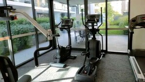 Un gimnasio con máquinas de cardio, una cinta de correr y un espejo grande.