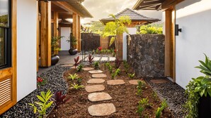 A pathway with stepping stones leading to a wooden structure with a tiled roof.