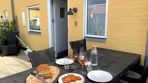 Een eettafel met stoelen, een waterfles, wijnglazen en borden met eten.