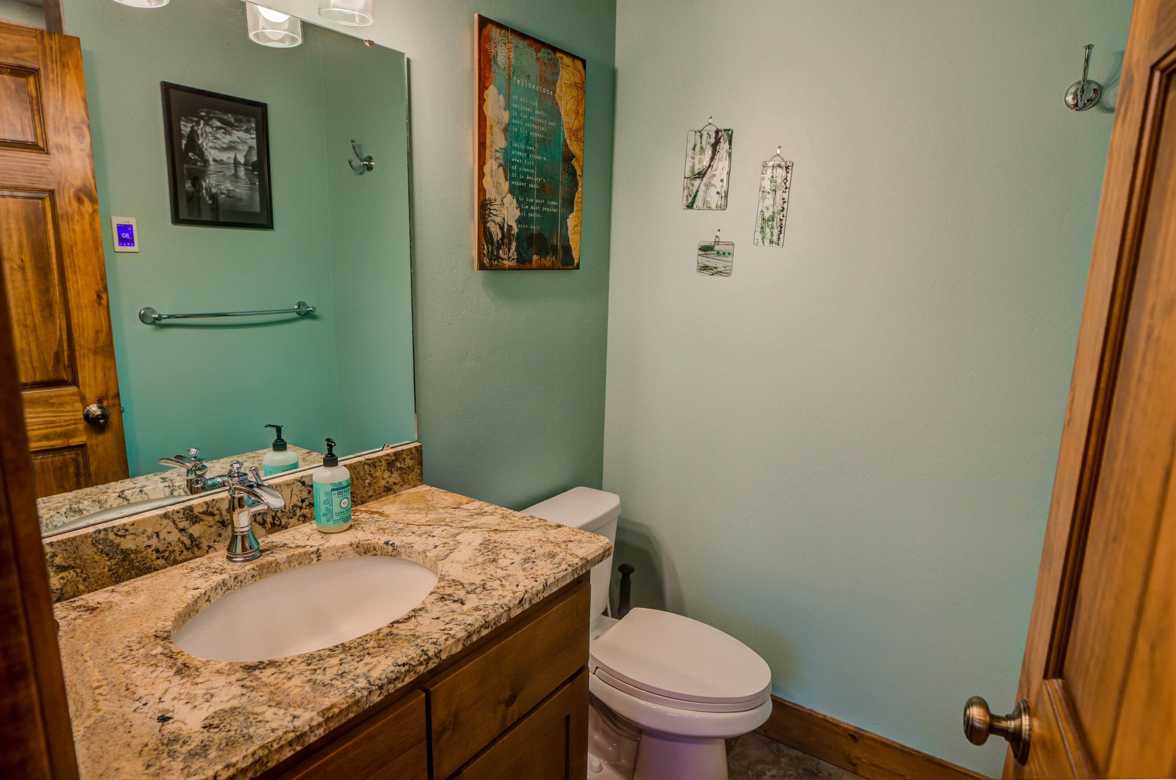 A bathroom with a granite sink, a white toilet, and a wooden door.