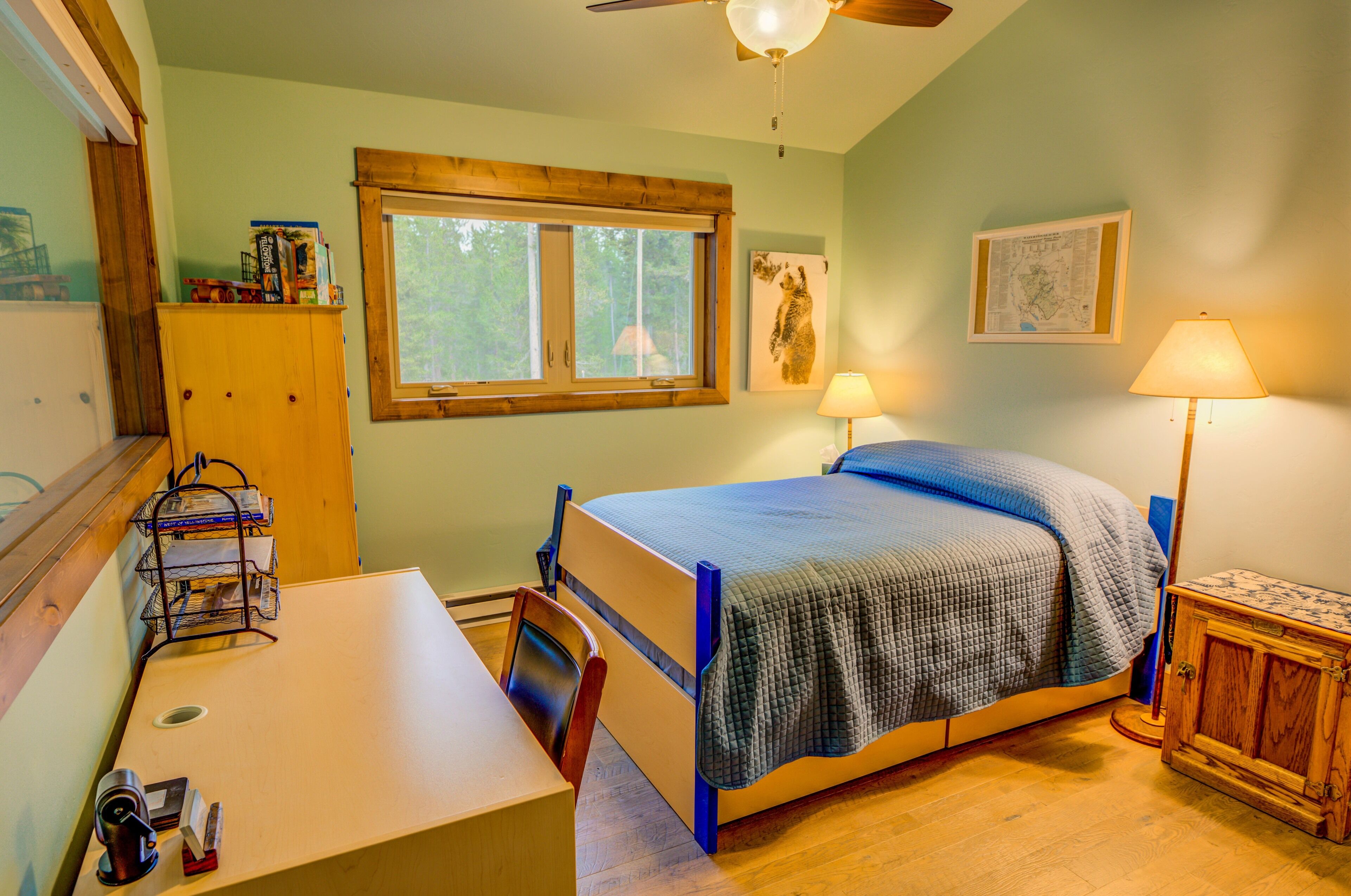 Een slaapkamer met een bed, bureau, stoel, raam en een kaart aan de muur.