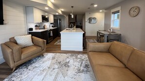 Une cuisine moderne avec des meubles blancs, un îlot central et un coin repas comprenant une petite table et des chaises.