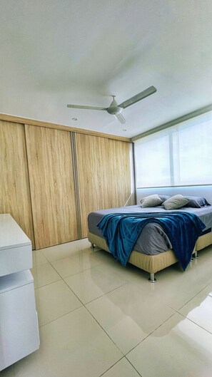 Un dormitorio con cama, ventilador de techo, armario y ventana.