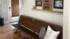 A wooden bench with a pillow, a door with a brown blind, and a wall with decorative metal and wooden elements. - Craftsman style family gathering home close to Guntersville (Scottsboro)
