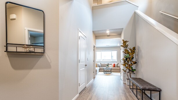 A hallway with a bench, a mirror, and a plant.
