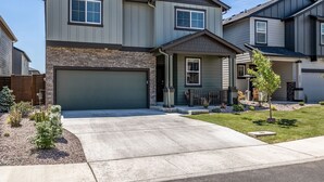 A two-story residential building with a stone facade, a garage, and a well-maintained lawn.