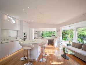 Una cocina moderna con una isla central, taburetes de bar y una mesa de comedor.