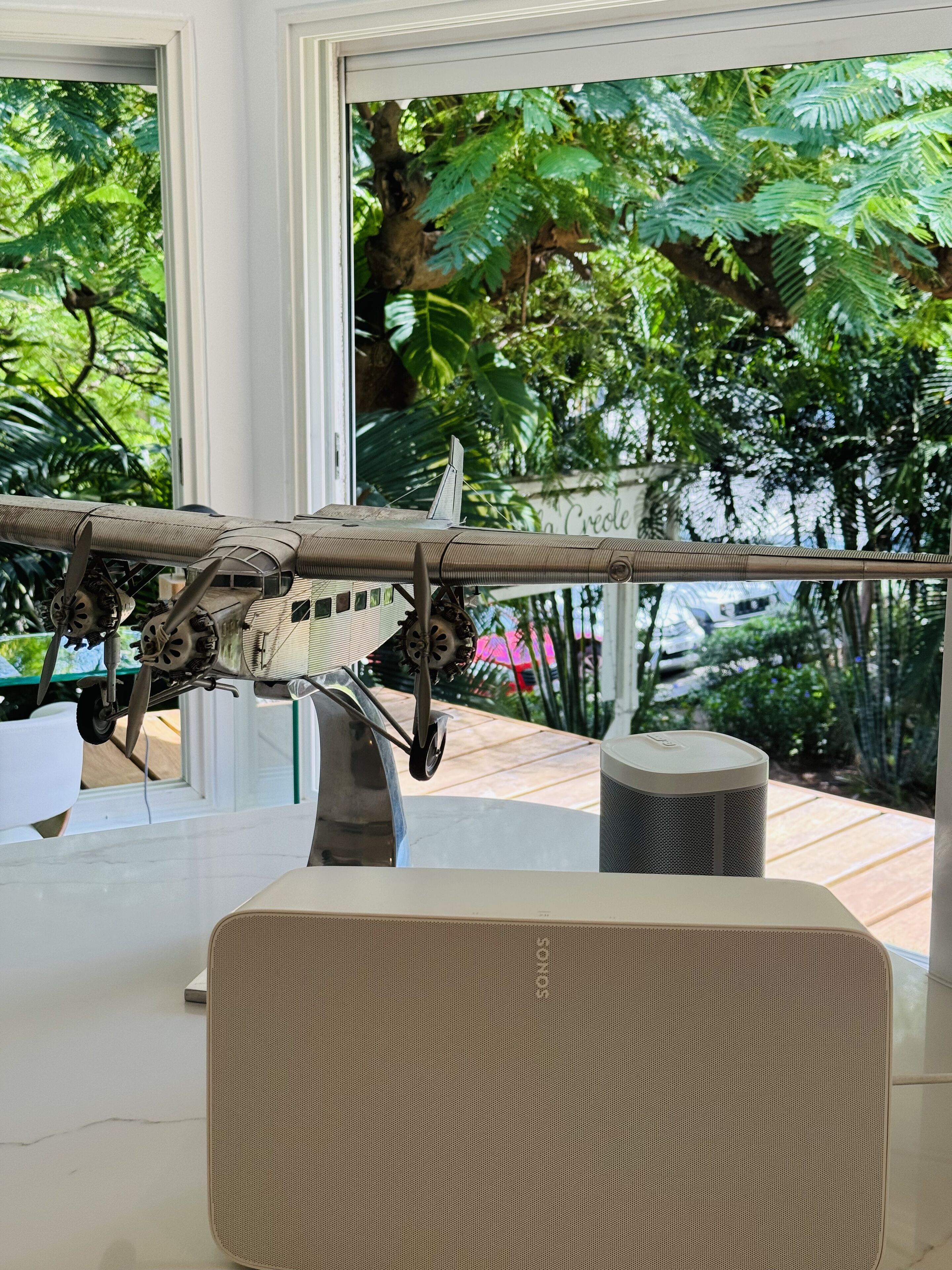 Un modèle d’avion est posé sur une table dans une pièce dotée de grandes fenêtres donnant sur un jardin.