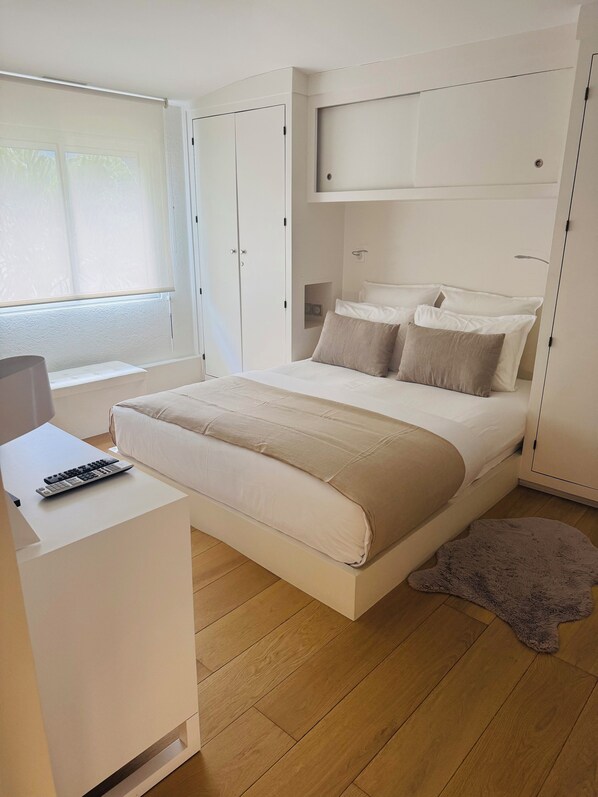 Ein modernes Schlafzimmer mit Bett, Nachttisch und einem Fenster mit Jalousien.