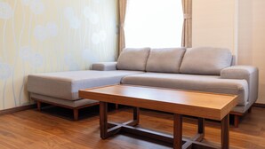 A modern living room with a sectional sofa, a wooden coffee table, and a patterned wallpaper. - Koubounoyu Honten (Izunokuni)
