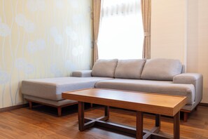 A modern living room with a sectional sofa, a wooden coffee table, and a patterned wallpaper. - Koubounoyu Honten (Izunokuni)