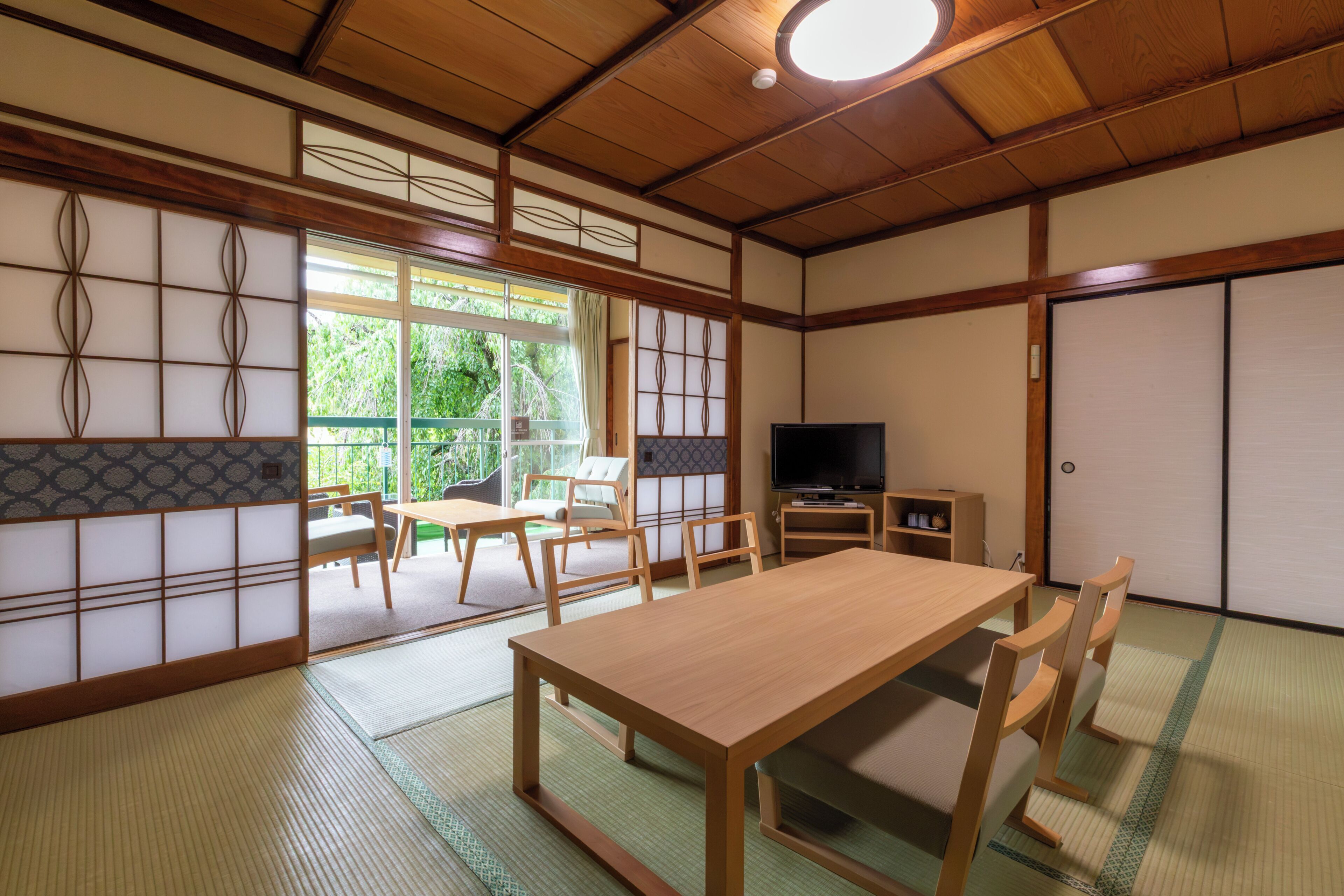 Una habitación tradicional japonesa con suelo de tatami, una mesa de madera baja y un televisor.