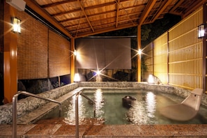 A hot spring bath area with wooden beams, tiled flooring, and stone walls. - Koubounoyu Honten (Izunokuni)