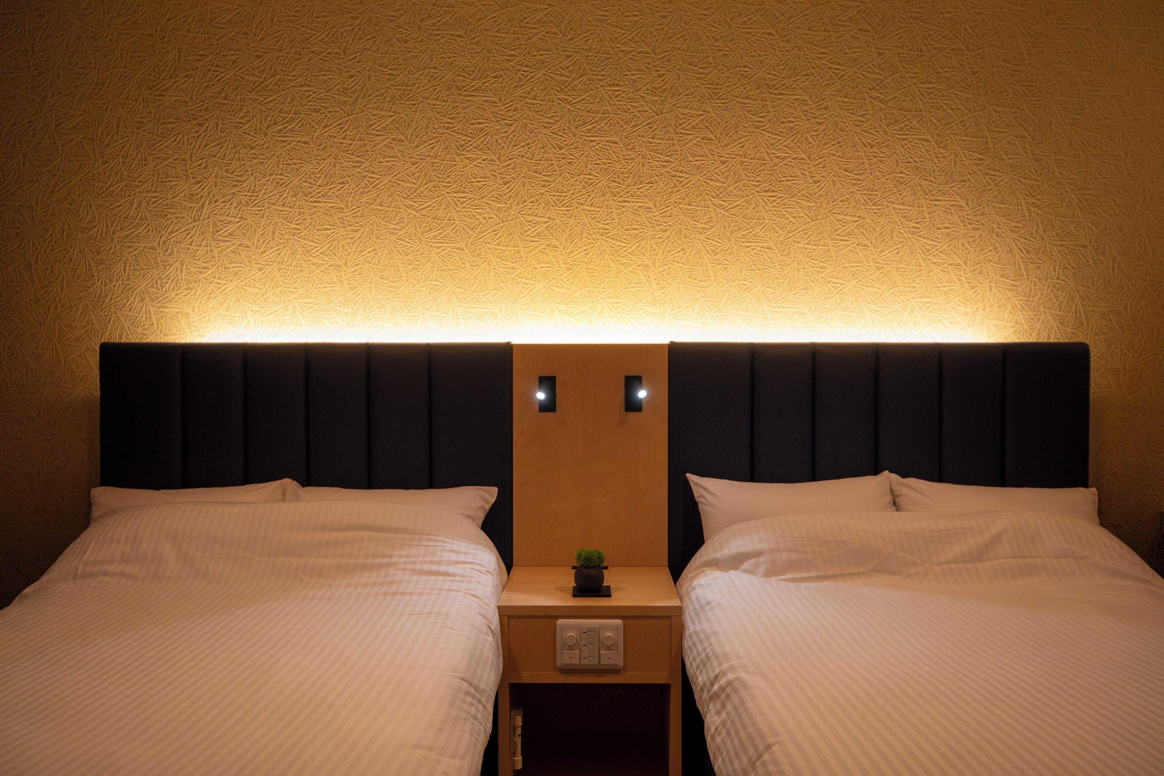 A double bed with a headboard, a bedside table with a lamp, and a small plant.